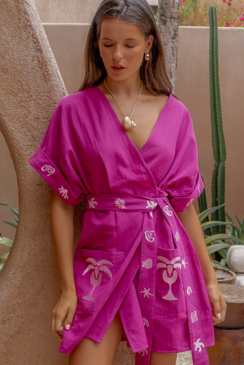 Woman wearing a pink dress with patterns in an outdoor setting