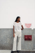 Girl wearing stripe pants against a wall.