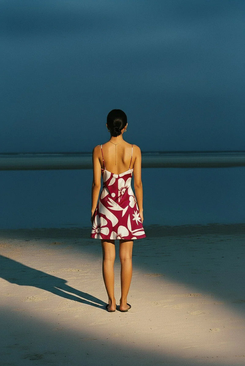 Tahiti mini slip dress from palm collective on a dark skin model against a peach wall.