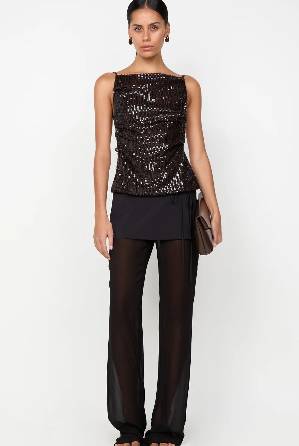 Woman wearing a black sequined top and black pants on a white background