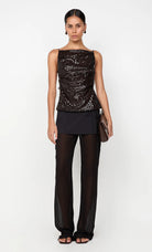 Woman wearing a black sequined top and black pants on a white background