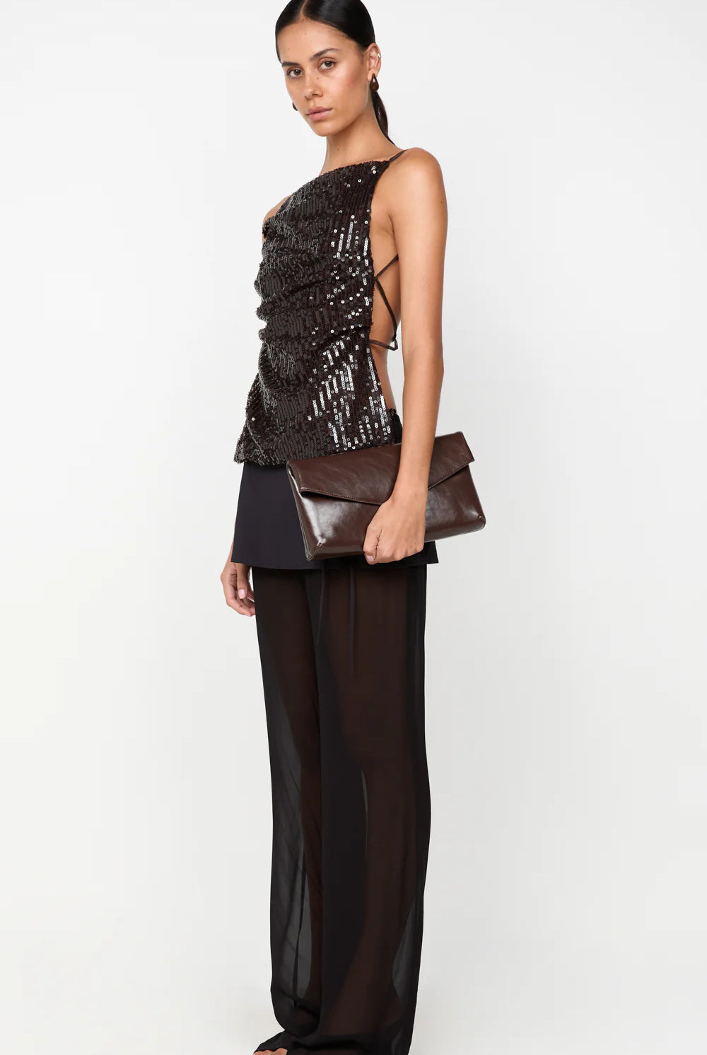 Woman wearing a black and gold outfit with a clutch on a white background