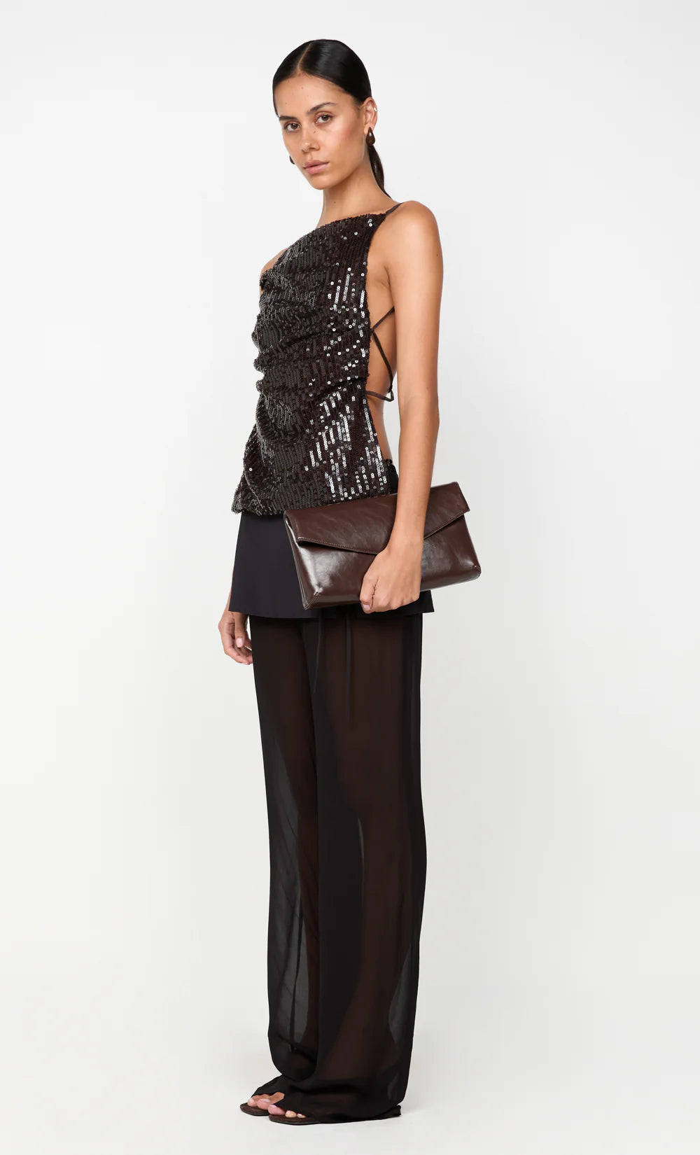 Woman wearing a black and gold outfit with a clutch on a white background