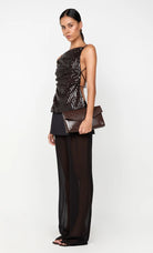 Woman wearing a black and gold outfit with a clutch on a white background