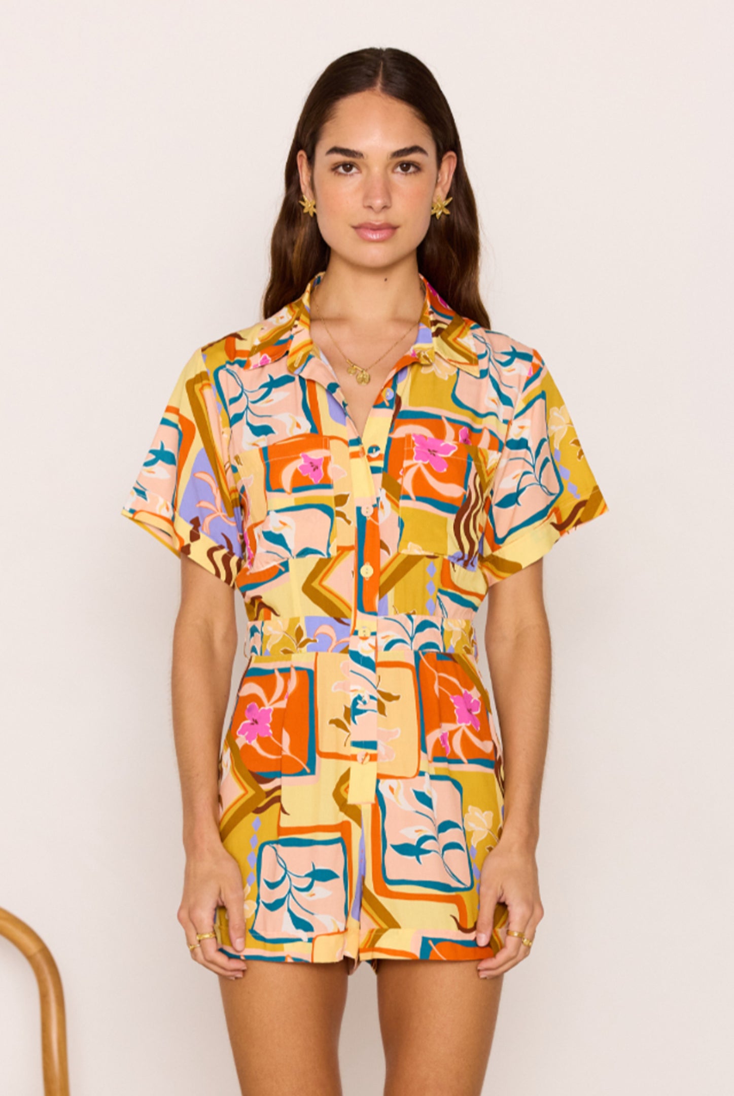 Woman wearing a colorful patterned dress against a plain background