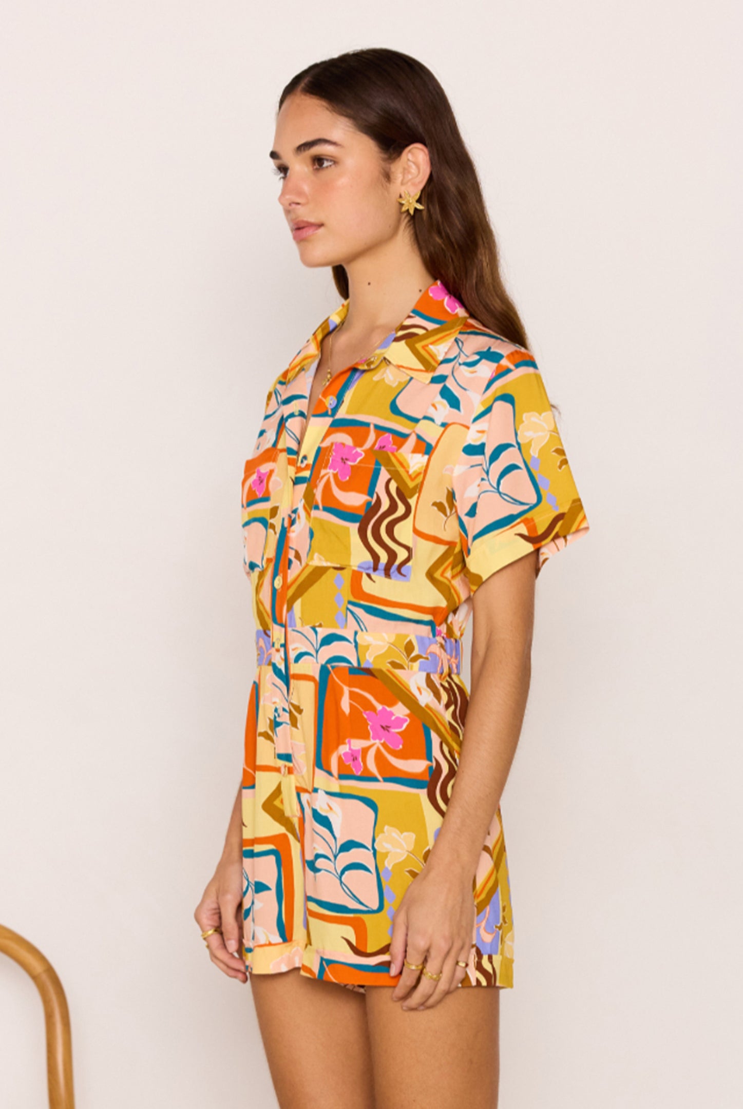 Woman wearing a colorful patterned shirt dress against a plain background
