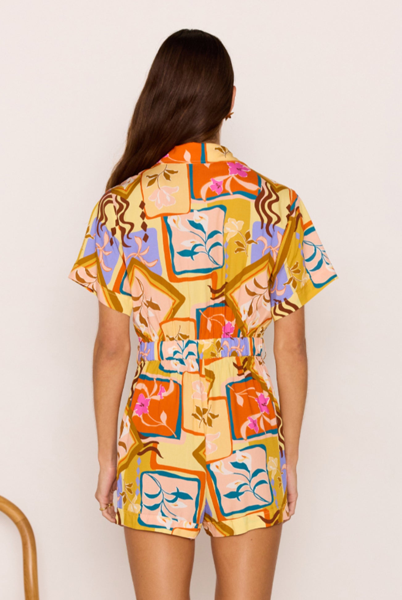 Woman wearing a colorful patterned dress against a plain background