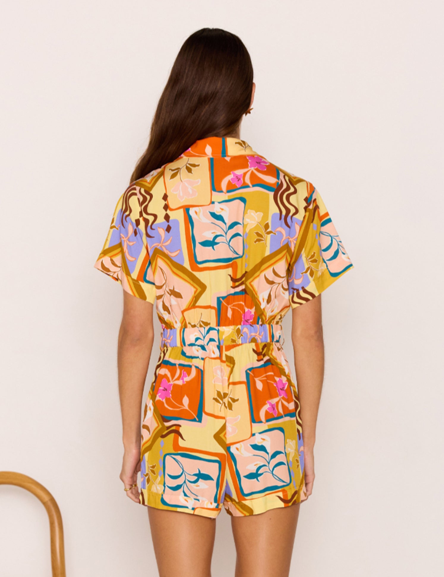 Woman wearing a colorful patterned dress against a plain background