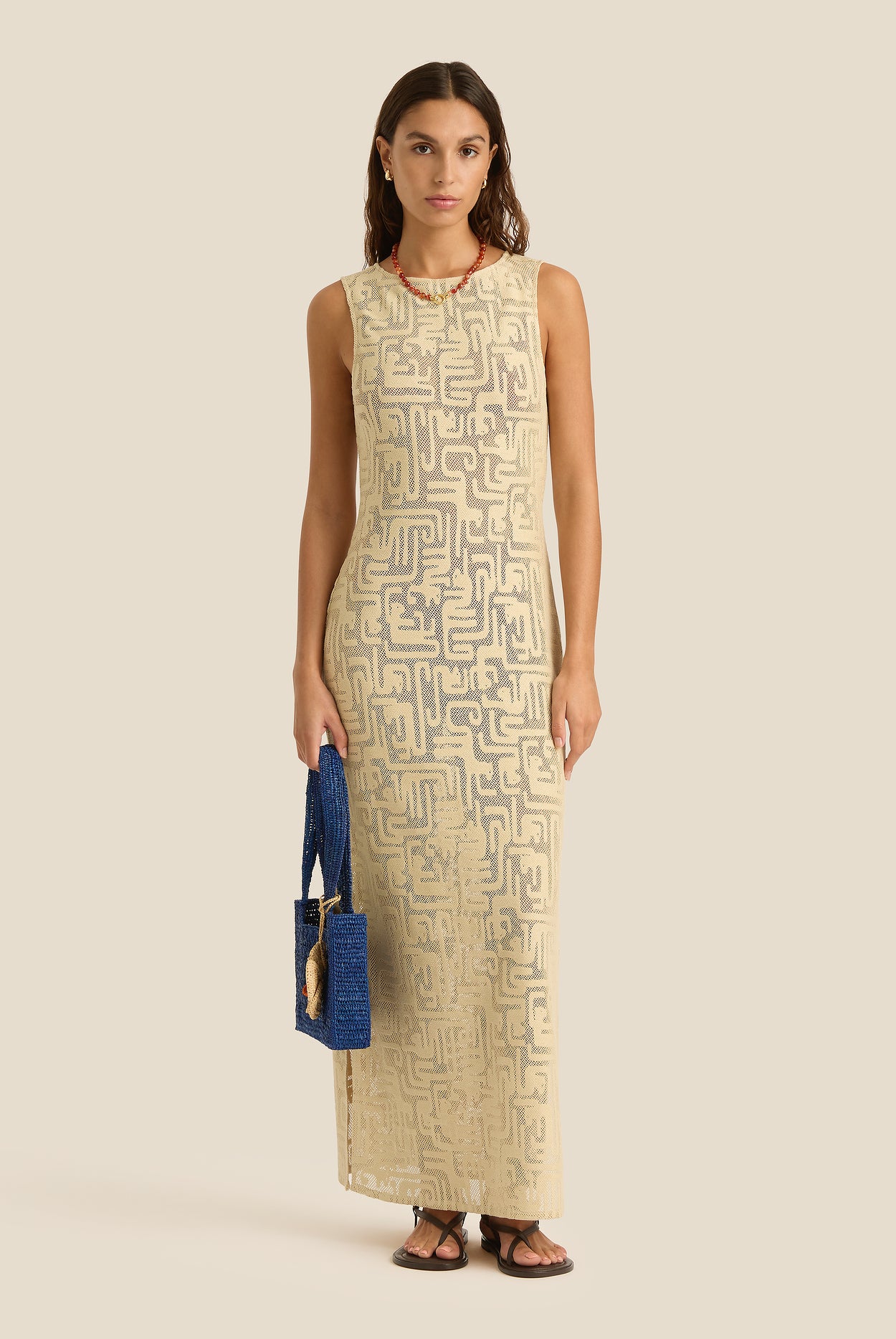 Woman wearing a beige sleeveless dress with geometric pattern on a beige background