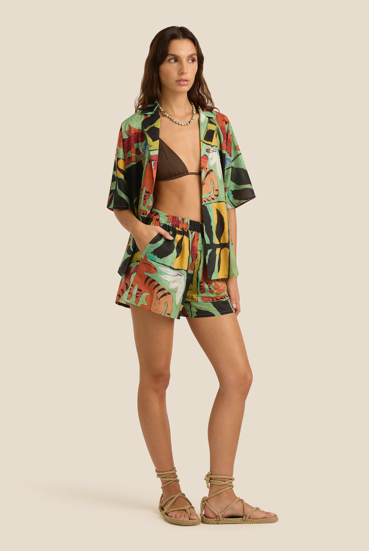 Woman wearing a colorful kimono-style jacket and shorts on a beige background