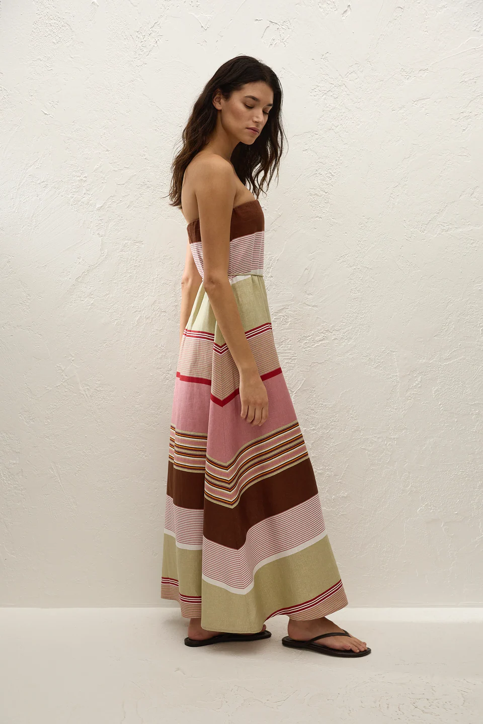 Woman wearing a colorful striped dress against a white background
