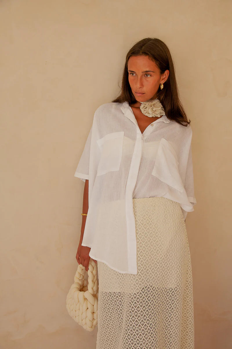 Woman wearing a white blouse and beige skirt against a beige background