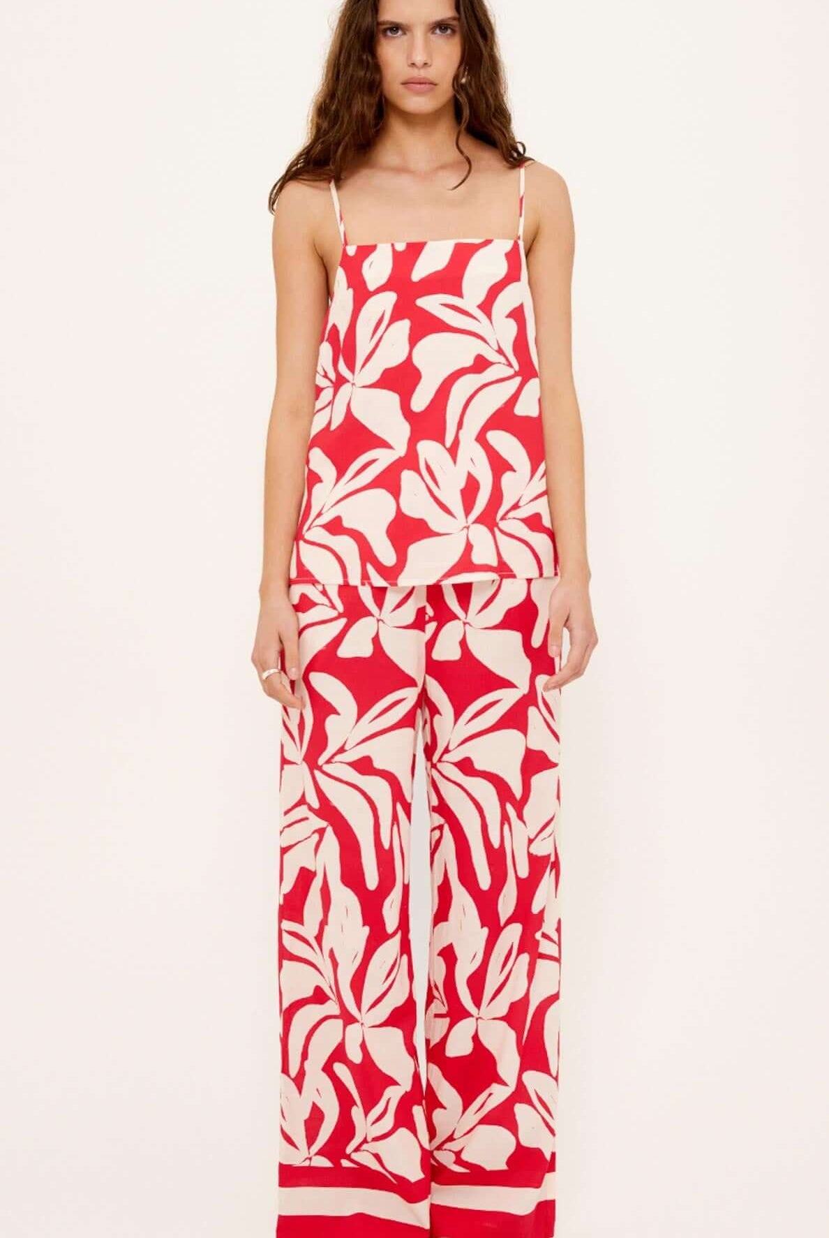 Woman wearing a red and white floral jumpsuit on a white background