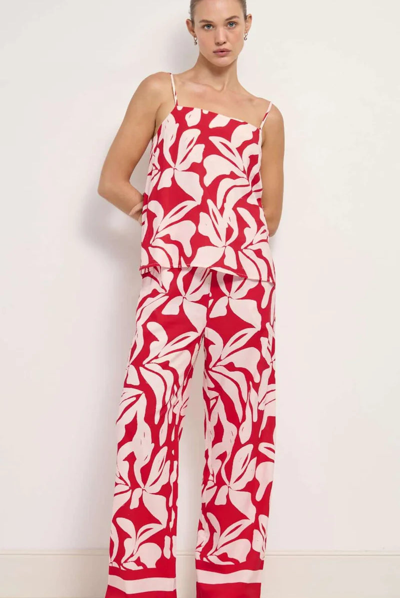 Woman wearing a red and white floral jumpsuit against a white background