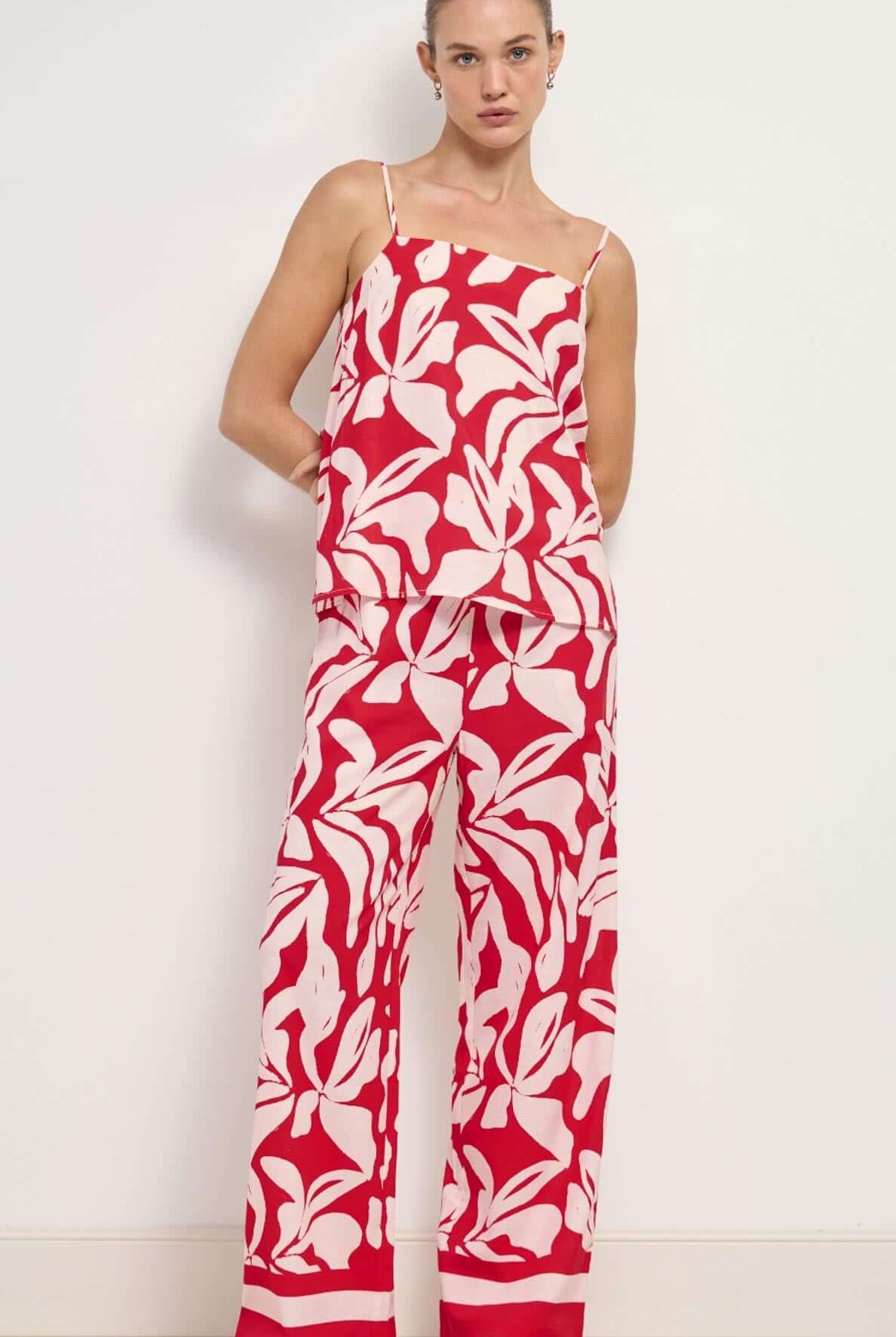 Woman wearing a red and white floral jumpsuit against a white background