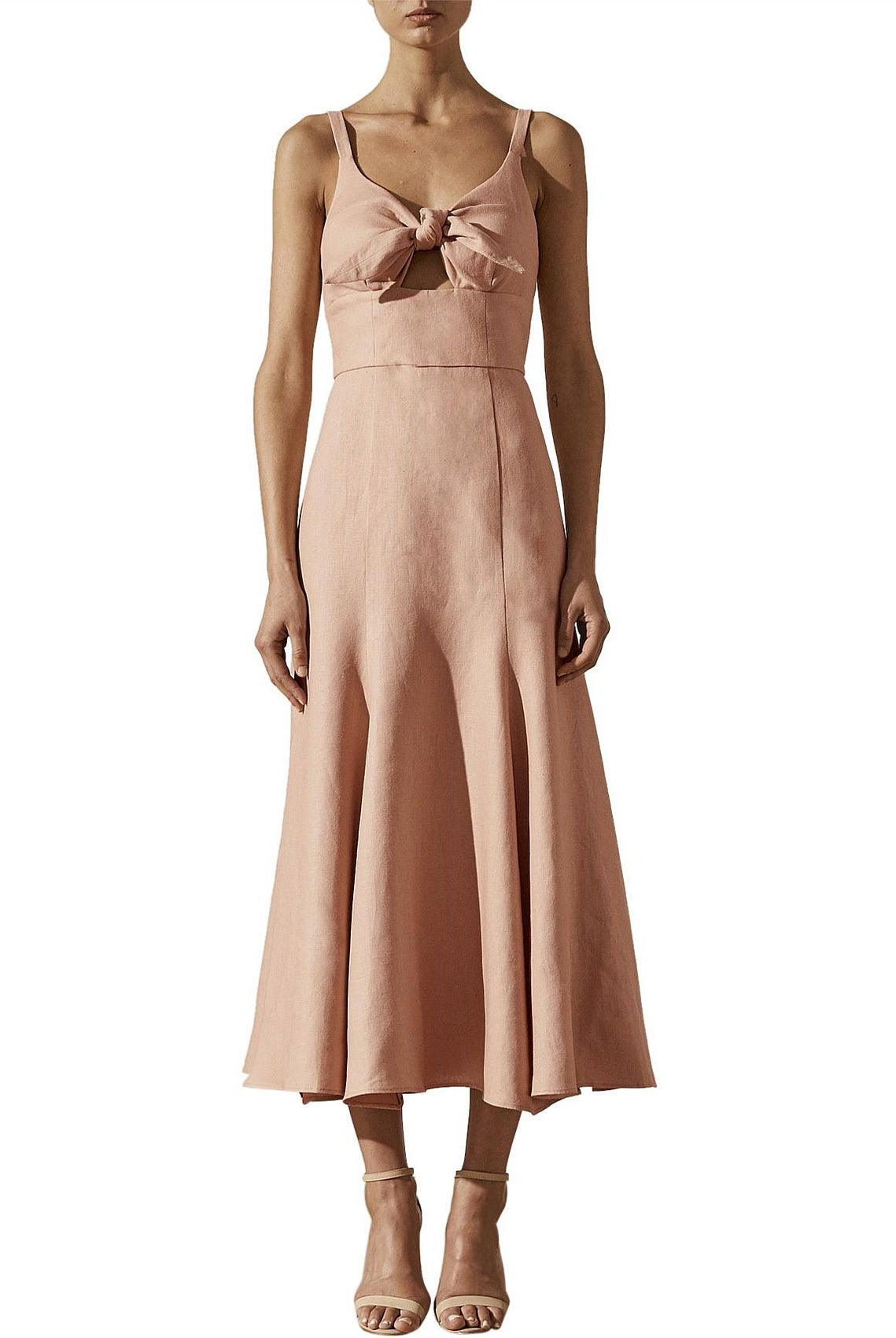 Woman wearing a pink dress with a bow detail on a white background