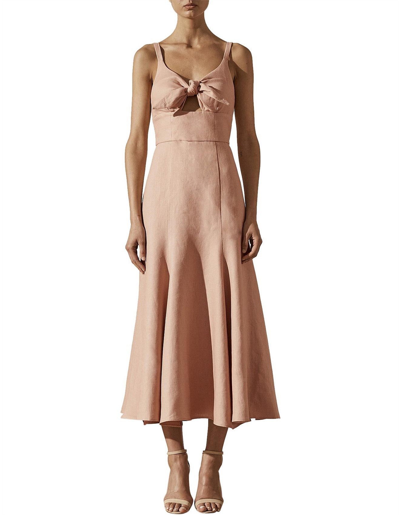 Woman wearing a pink dress with a bow detail on a white background