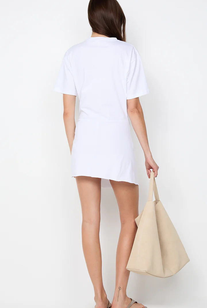 Person wearing a white t-shirt and holding a beige handbag on a plain background