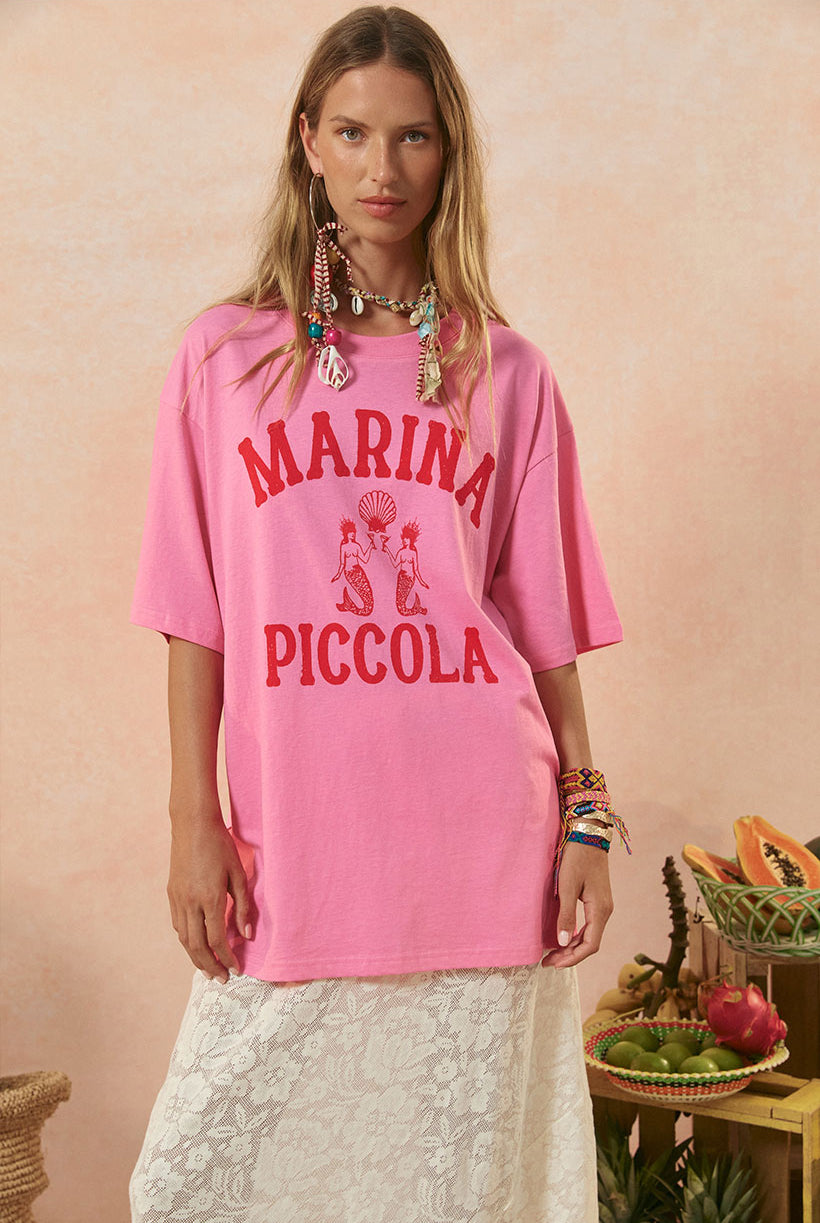 Woman wearing a pink 'Marina Piccola' t-shirt against a beige background