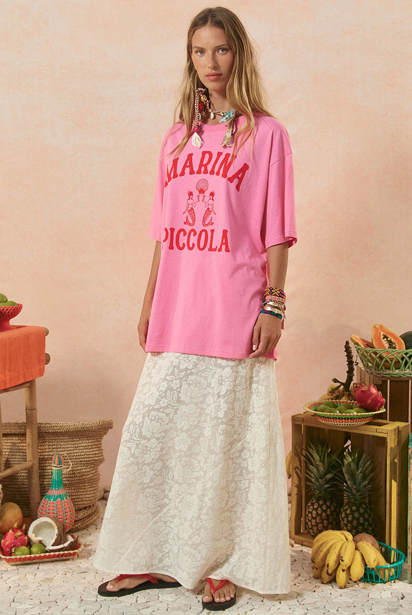 Woman wearing a pink 'Marina Piccola' shirt with a rustic background