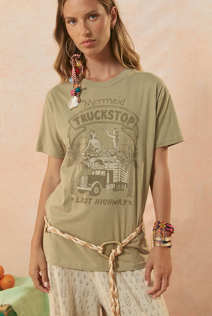 Woman wearing a green graphic t-shirt with a vintage truck design on a pink background