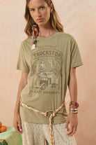 Woman wearing a green graphic t-shirt with a vintage truck design on a pink background