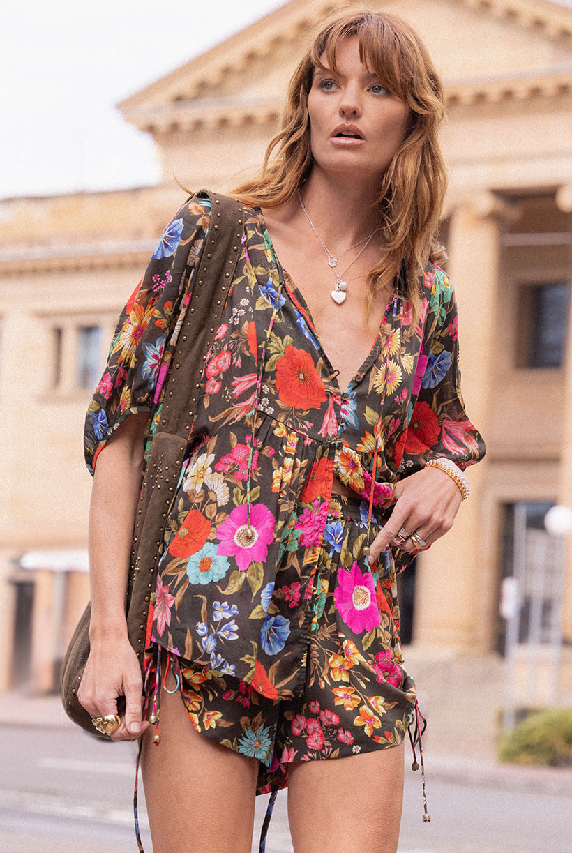 Woman wearing a colorful floral dress with a building in the background