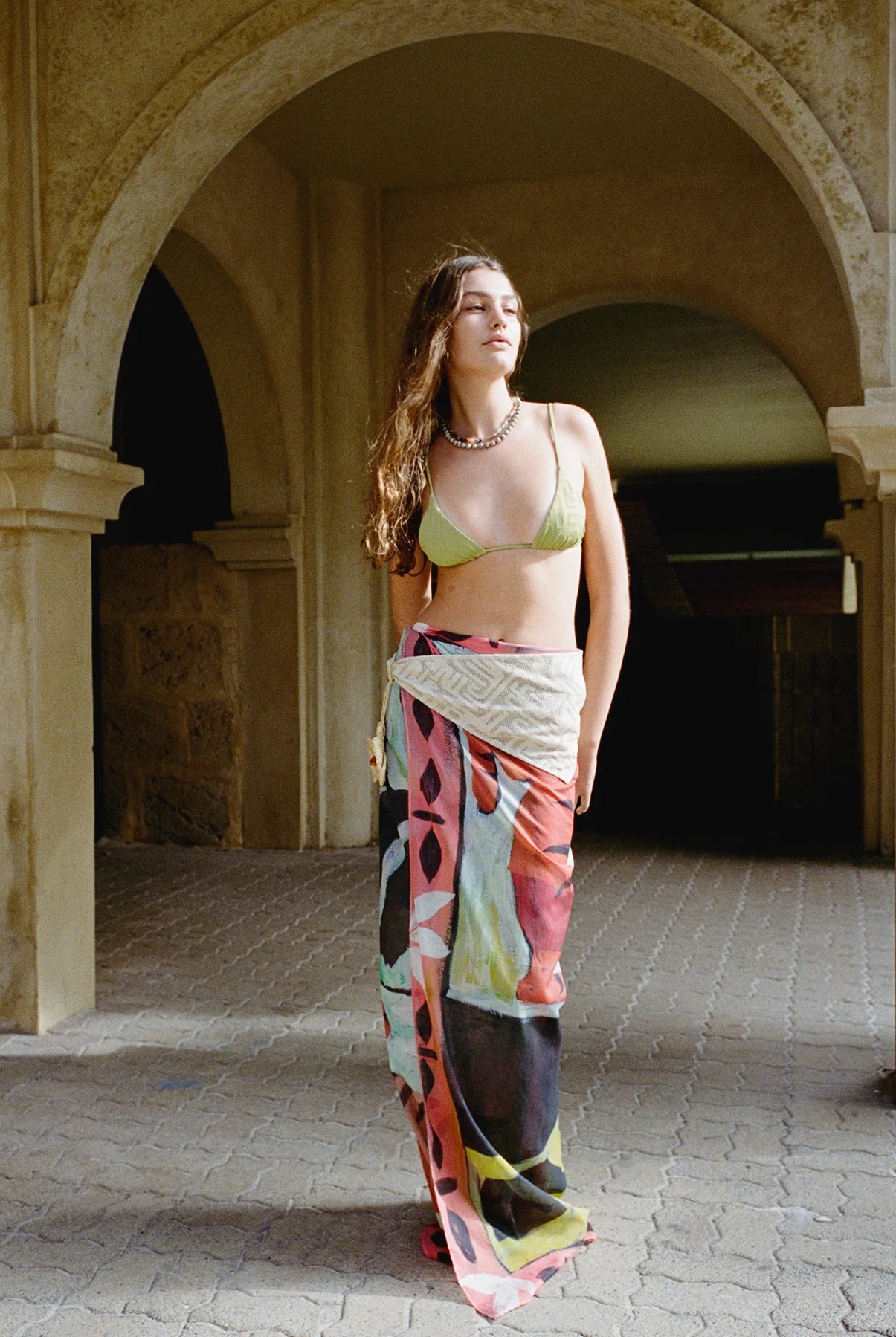Woman in a colorful dress standing under an archway