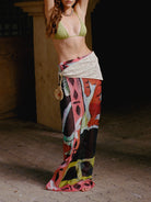 Woman wearing a green bikini top and colorful sarong in a dimly lit setting