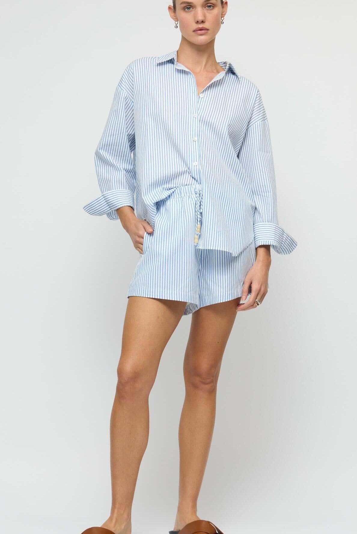 Woman wearing a light blue striped dress with a white background