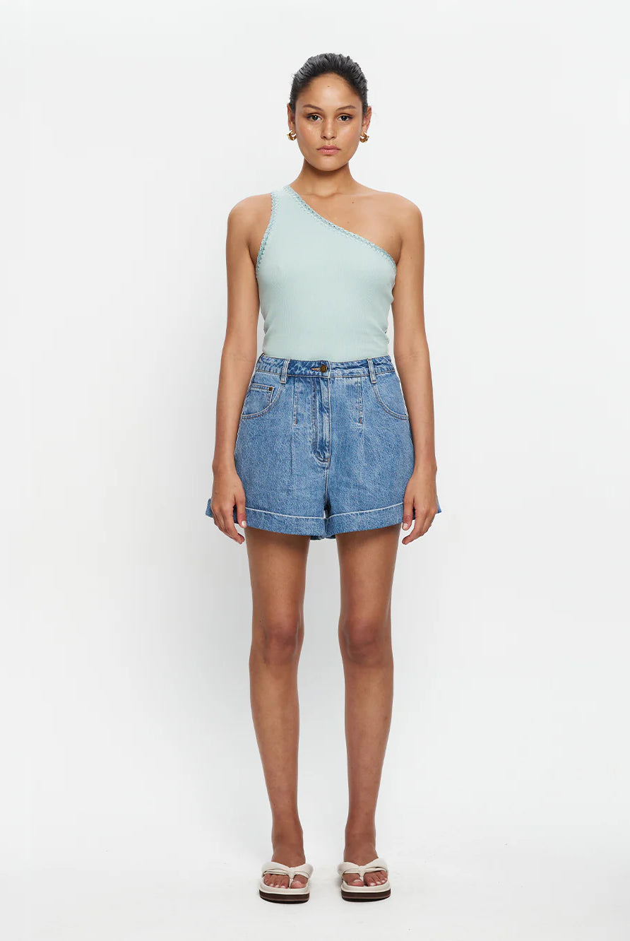 Woman wearing mint one shoulder tank and denim shorts