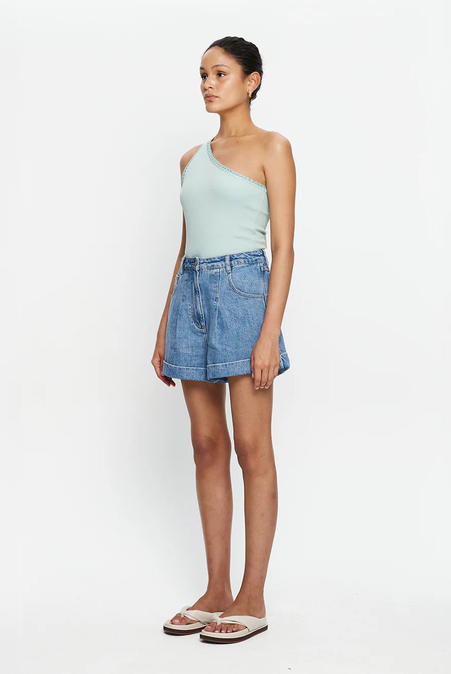 Woman wearing mint one shoulder tank and lightwash denim shorts