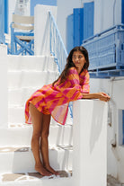 Woman in a colorful dress standing on white steps with blue railings in the background
