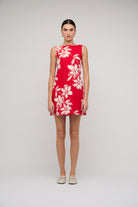 Red dress with white floral pattern worn by a model on a plain background