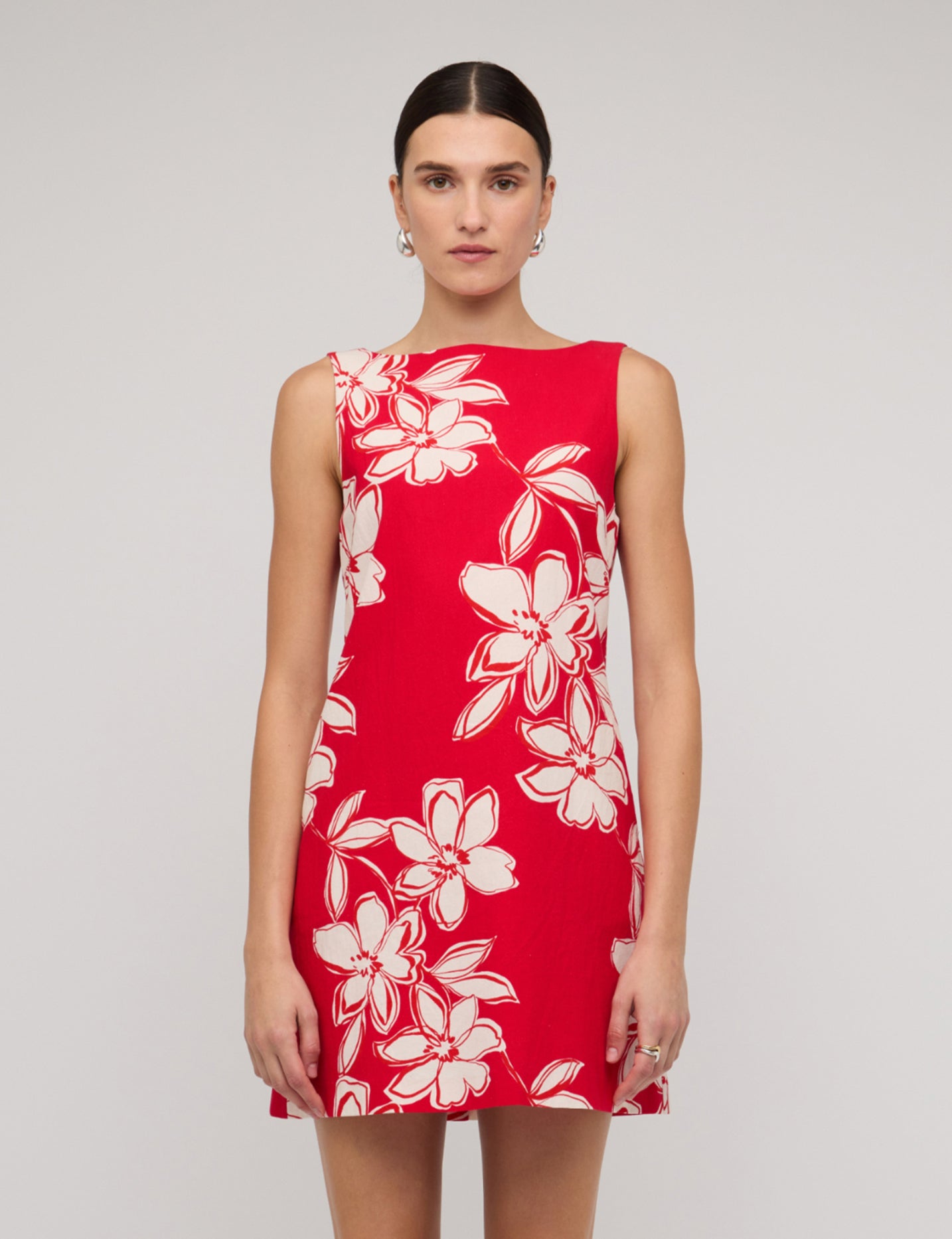 Red dress with white floral pattern worn by a model on a plain background
