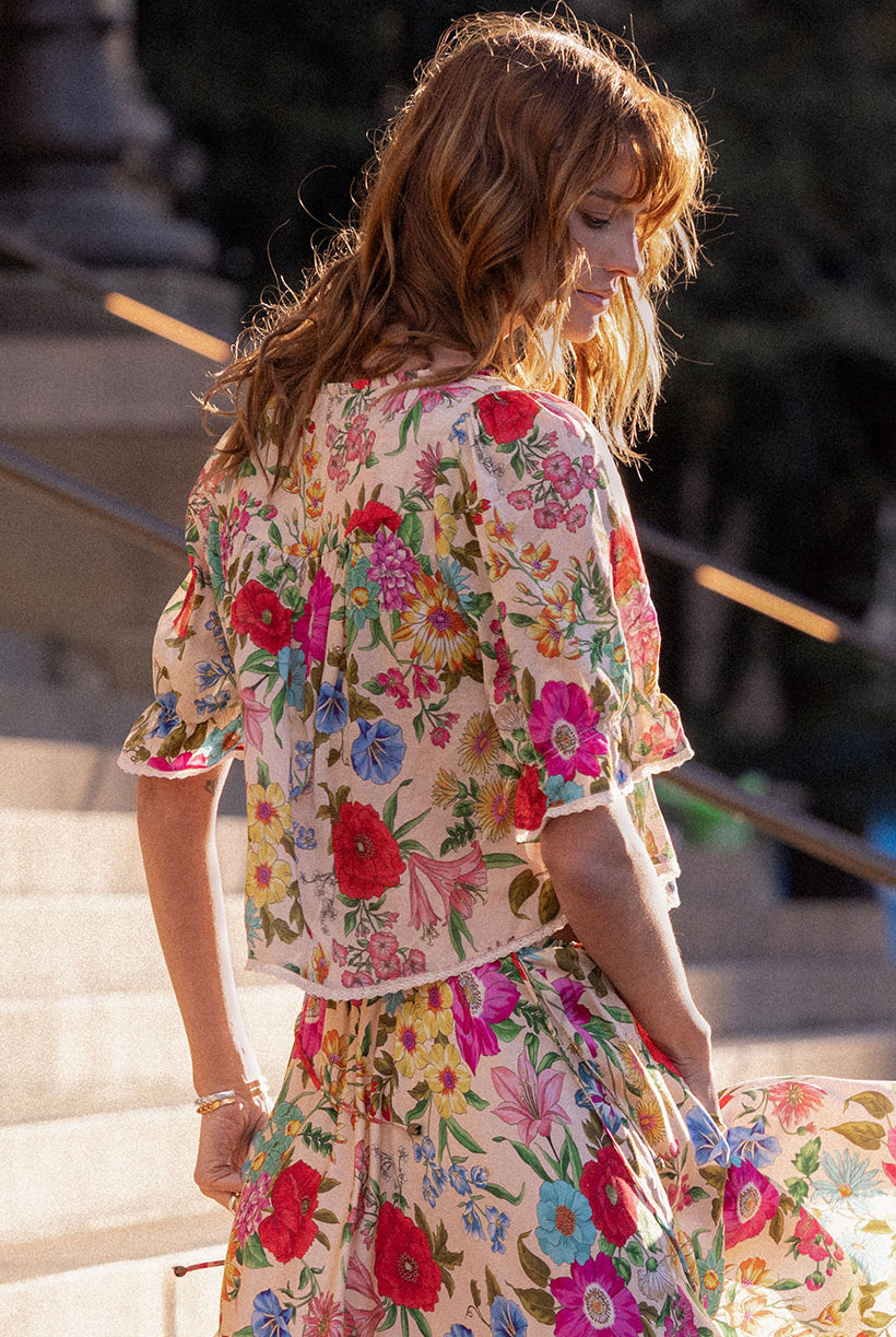 Woman wearing a floral dress standing outdoors on steps.