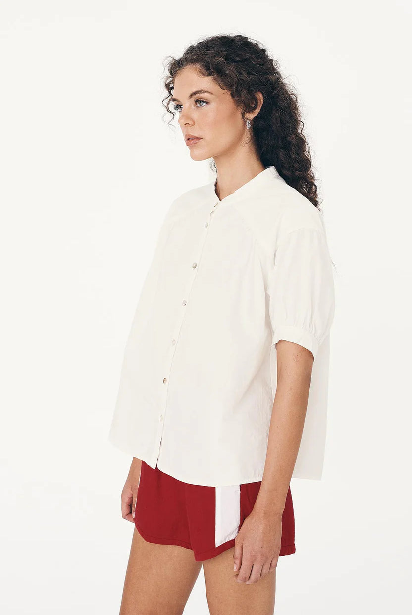 Woman wearing a white blouse and red shorts on a white background