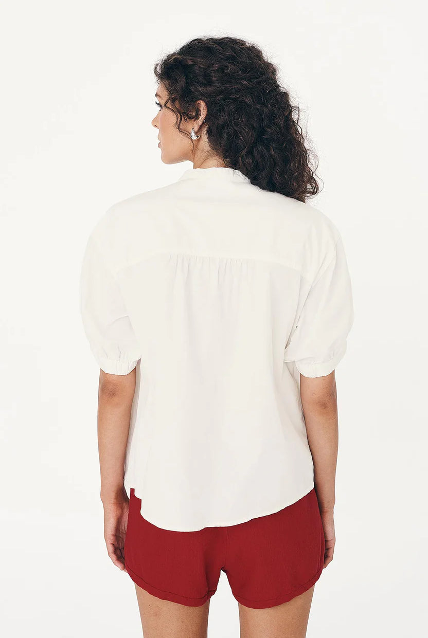 Woman wearing a white blouse and red shorts on a plain background