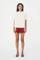 Woman wearing a white blouse and red shorts on a white background
