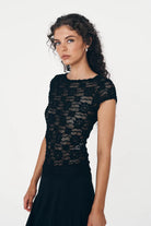 Woman wearing a black lace top against a white background