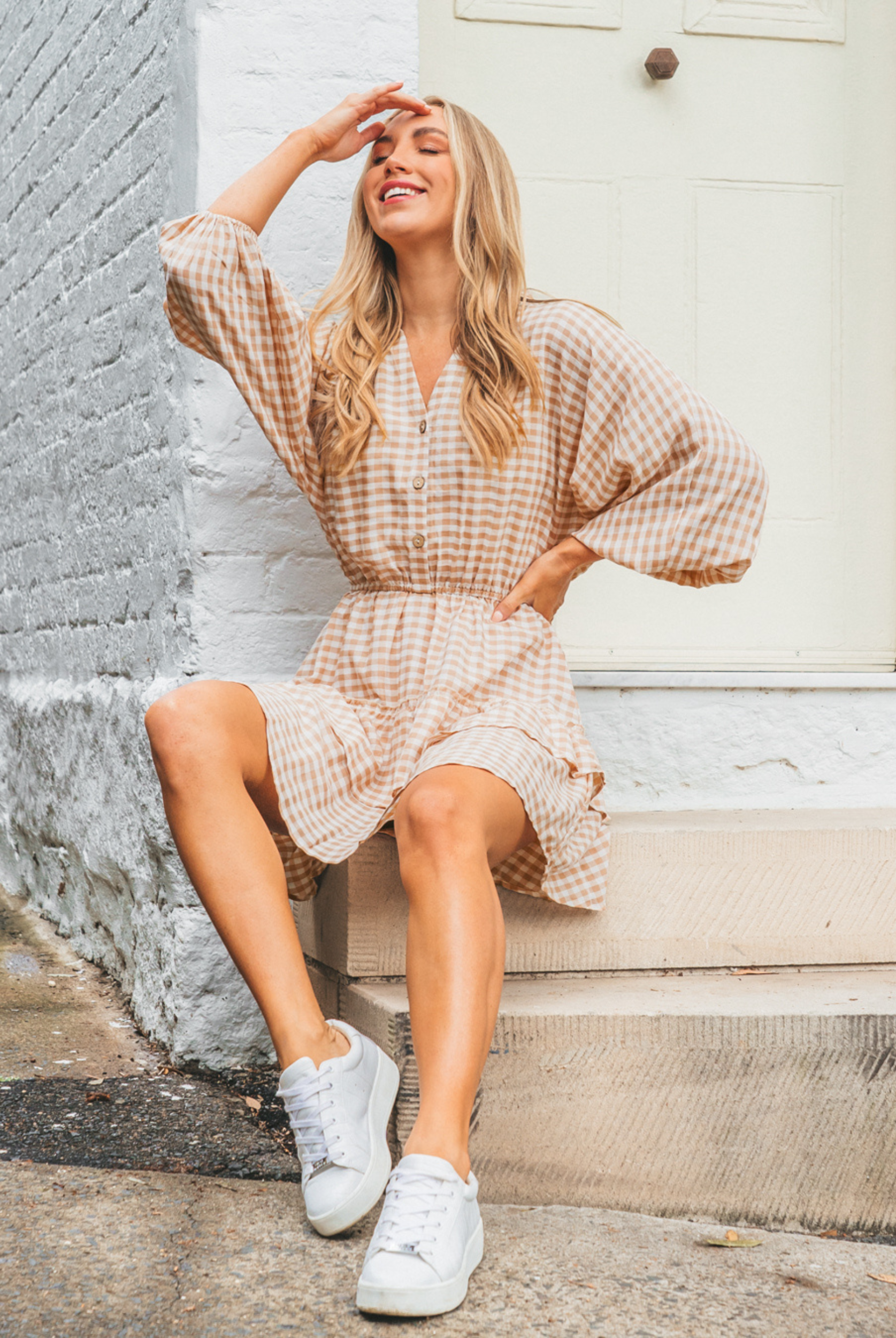Model wearing neutral and white gingham shirt dress with functional button placket and elasticated waistband