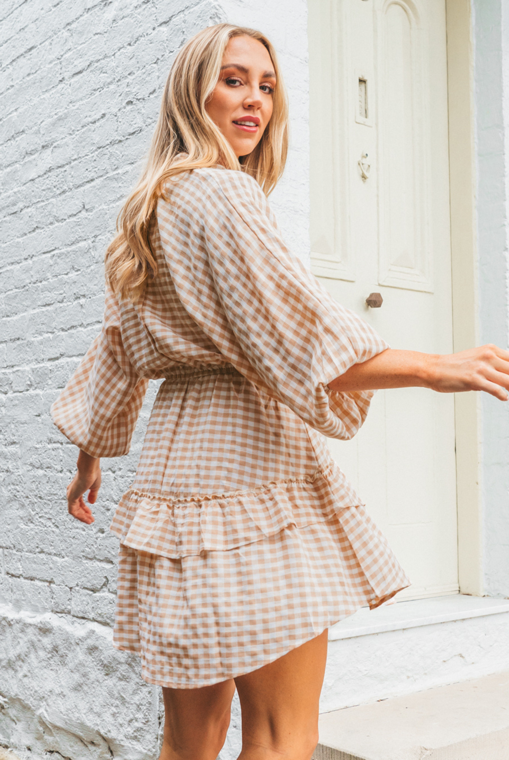 Model wearing neutral and white gingham shirt dress with functional button placket and elasticated waistband