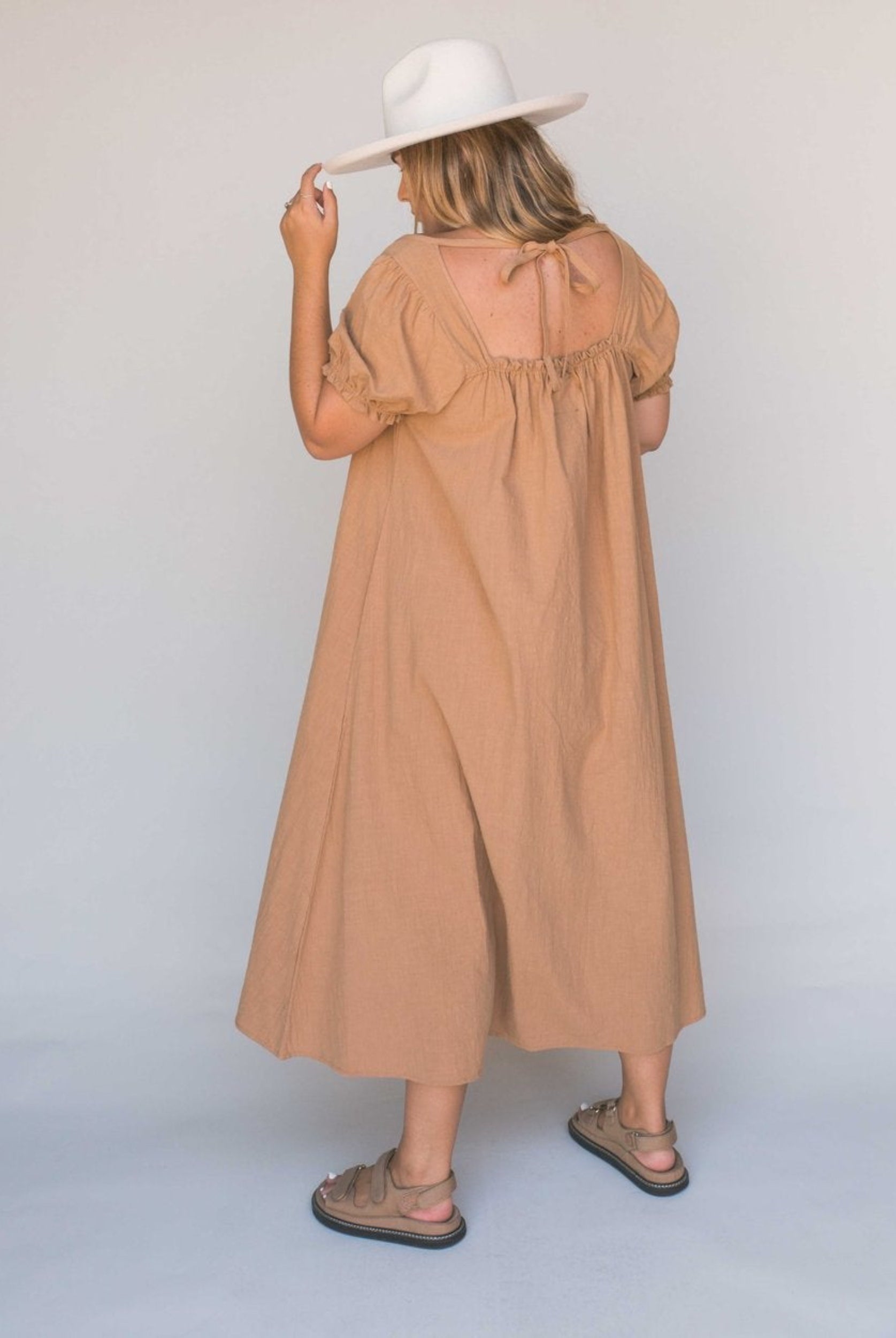 Model shot from the back wearing beige midi dress