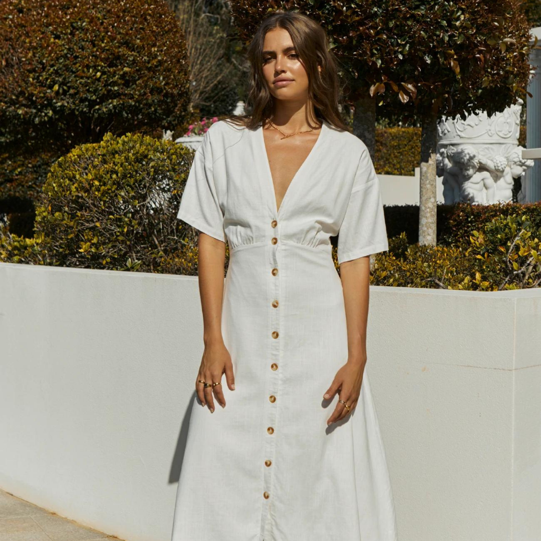 Brunette Model wearing the Marnie Midi Dress in white with buttons down the front and a short sleeve