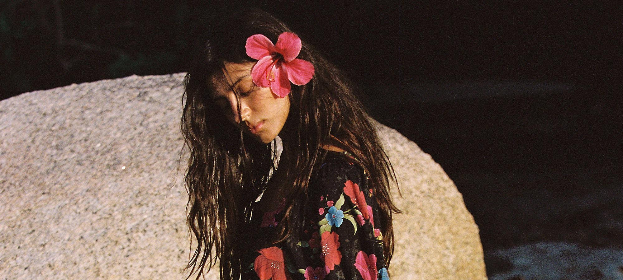 Model in the Spell Isola Gown in Midnight Bloom with a pink flower in her hair