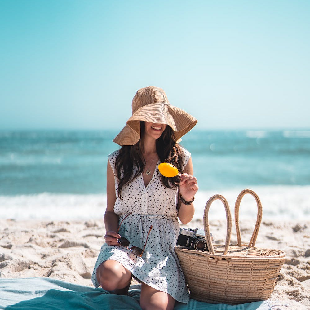 WOMAN SAT ON THE BEACH IN A HAT AND DRESS