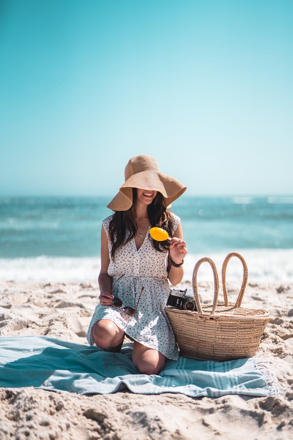WOMAN SAT ON THE BEACH IN A HAT AND DRESS