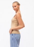 Model wearing a neutral tank with lightwash denim jeans