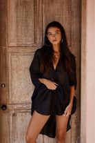 Woman wearing a black outfit standing against a wooden door.