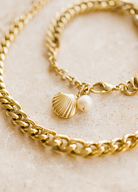 Gold chain link bracelet featuring a pearl and shell charm